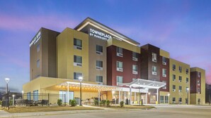 Monikerroksinen hotelli, jossa on katettu sisäänkäynti, ulkotila istumiseen ja kyltti, josta ilmenee, että se on TownePlace by Marriott -hotelliketjun hotelli.