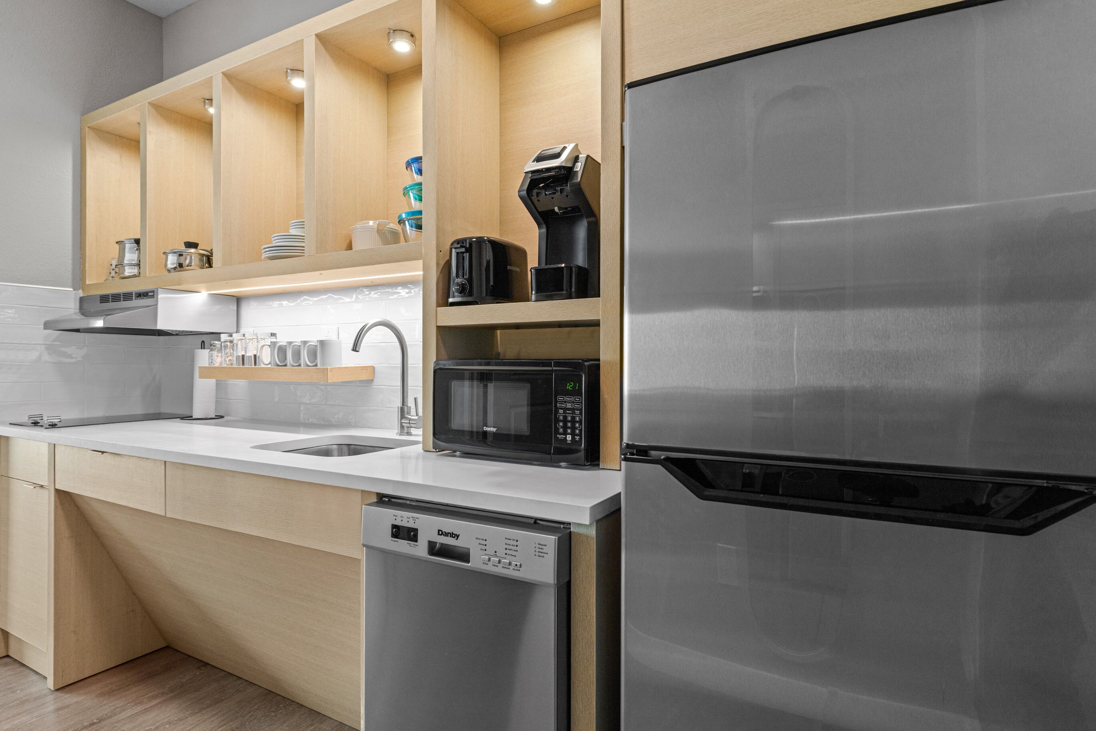 A modern kitchen with stainless steel appliances, wooden cabinets, and a dishwasher.
