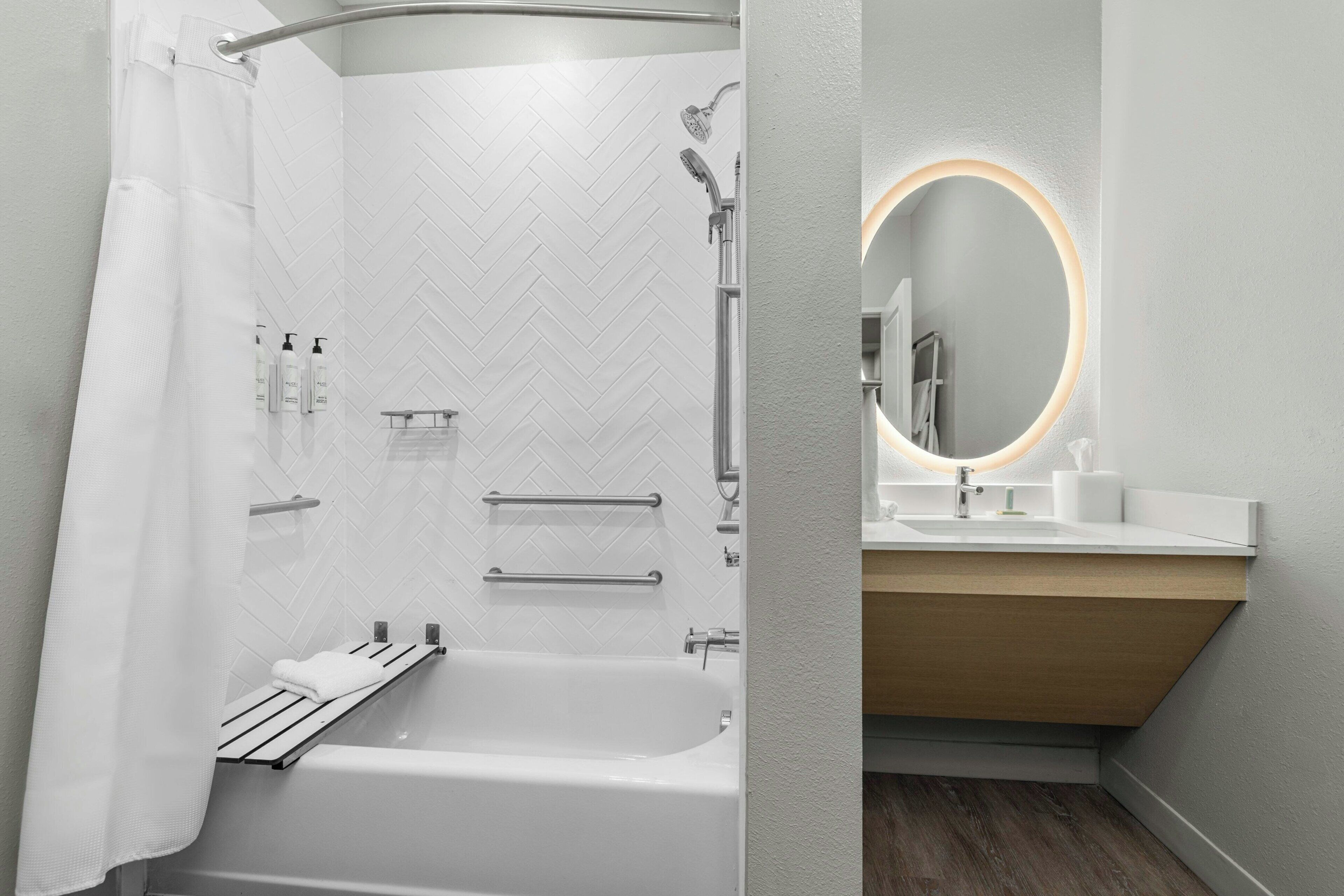 A modern bathroom with a shower, a bathtub, a vanity with a mirror, and a towel rack.