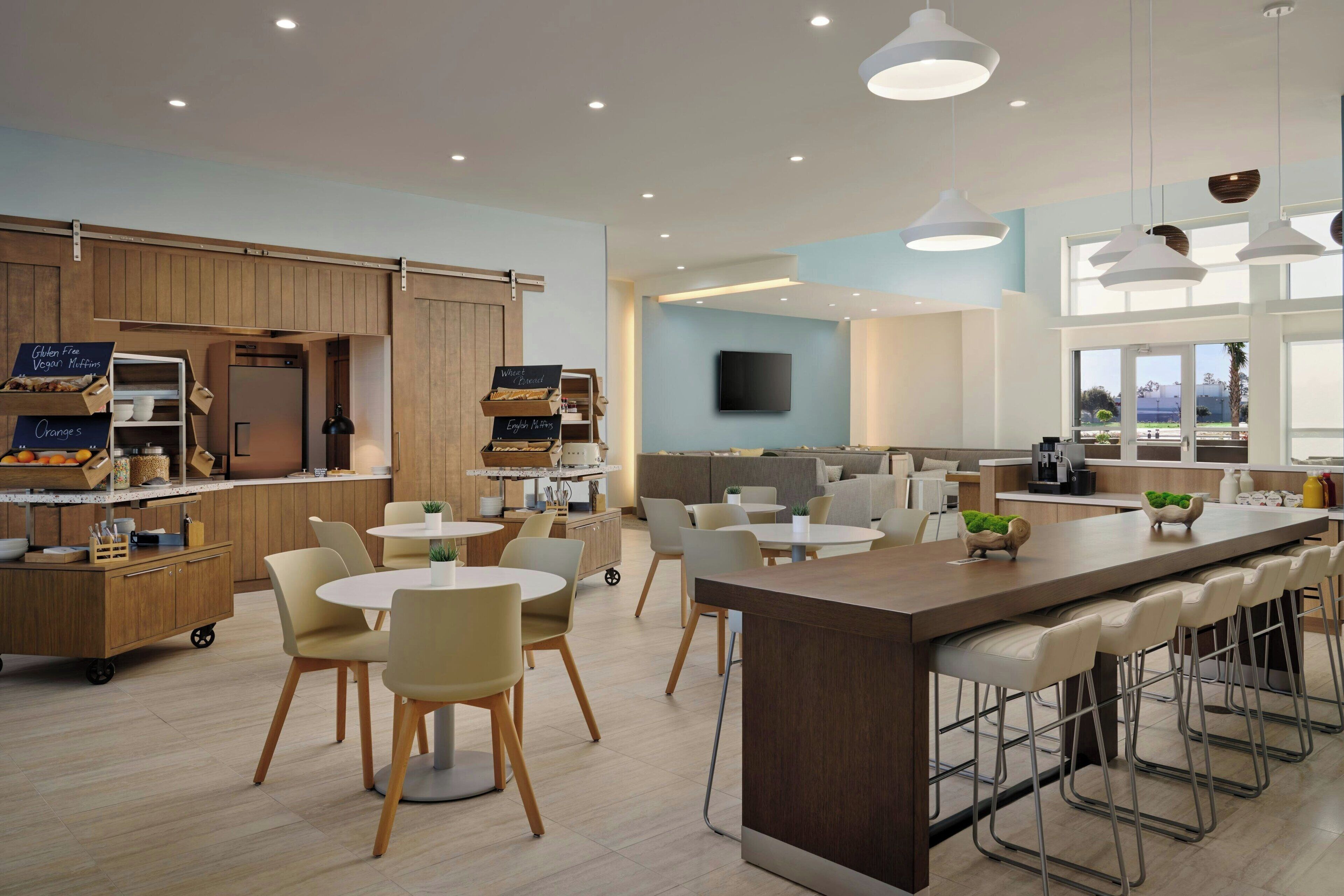 Una cocina moderna con una isla central, asientos tipo barra y una zona de comedor con mesas y sillas redondas.