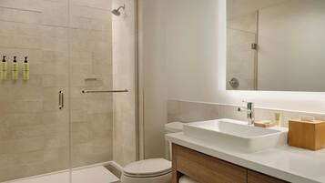 A modern bathroom with a glass shower enclosure, a white sink, and a wooden vanity.