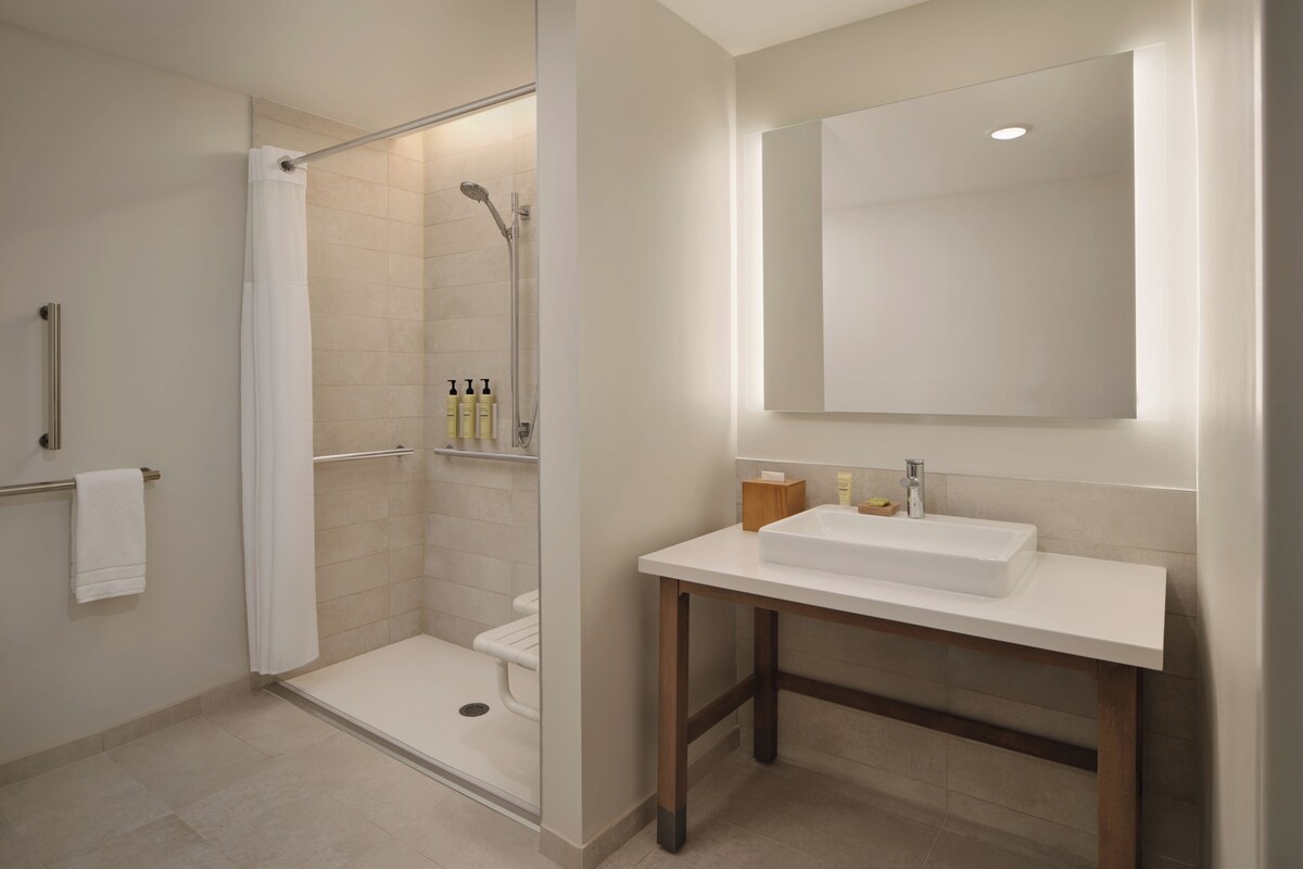 A modern bathroom with a glass-enclosed shower, a white sink, and a large mirror.