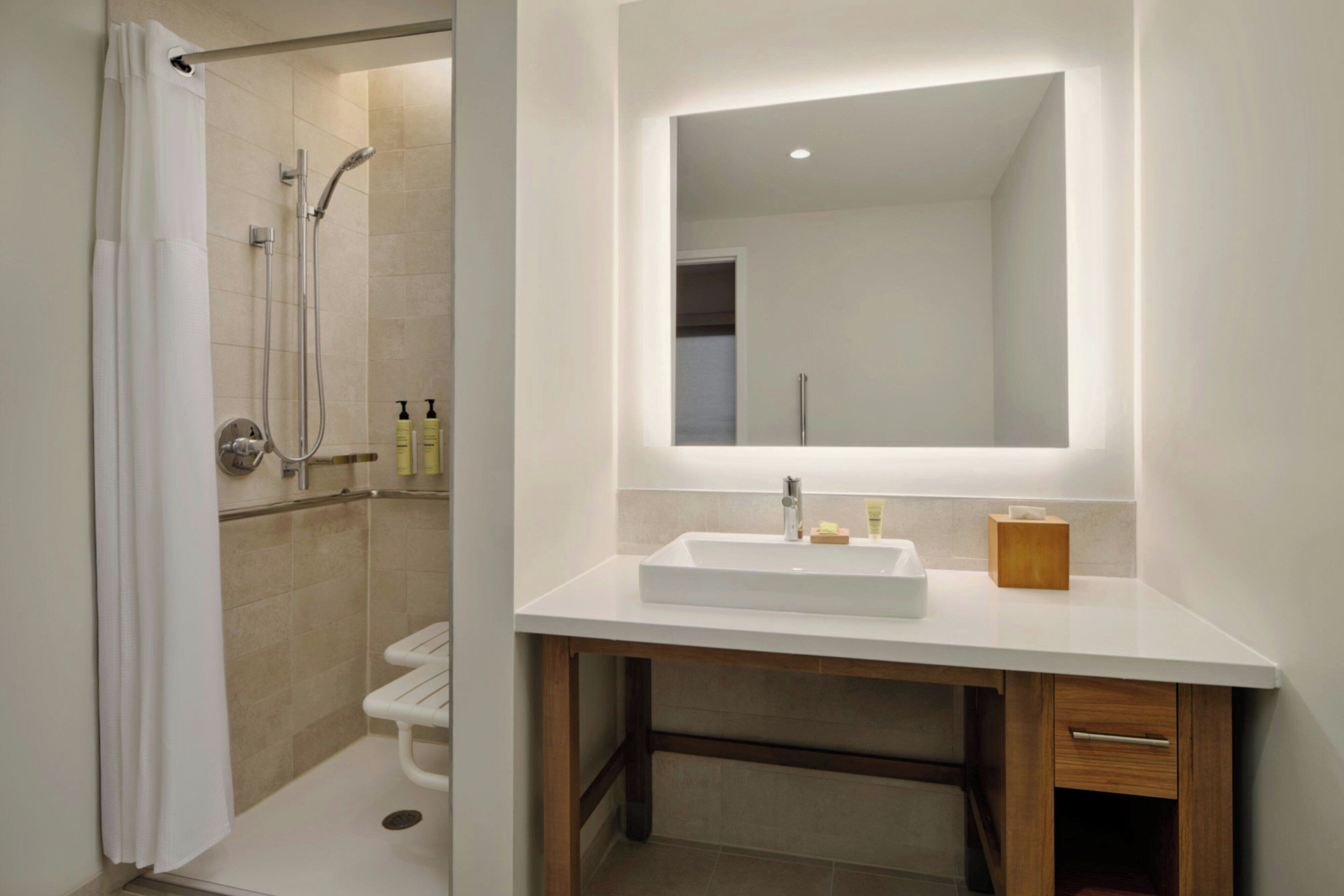 Un baño moderno con ducha, lavamanos y espejo.