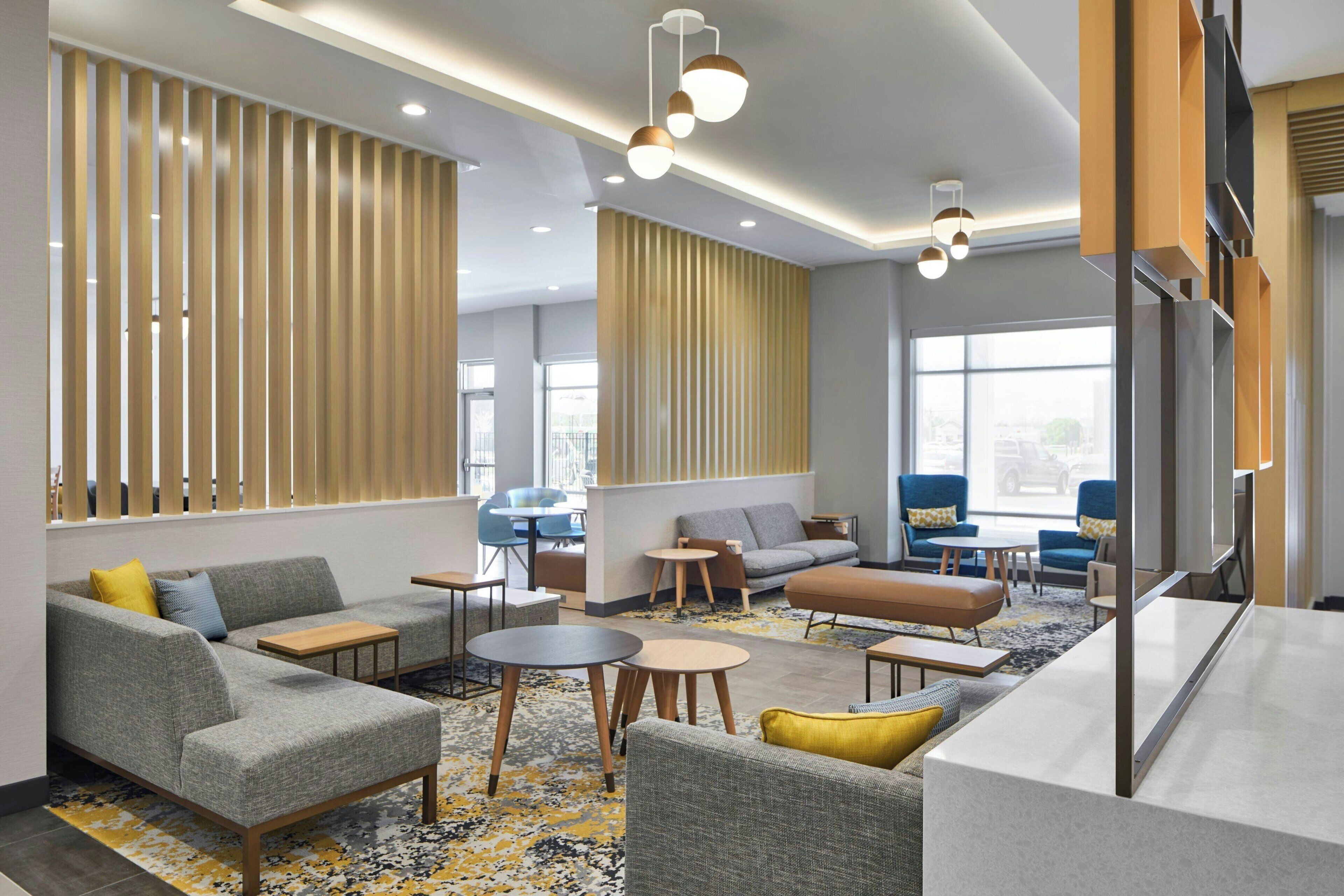 A modern lobby with a sectional sofa, round tables, and a large window providing a view of the outside.