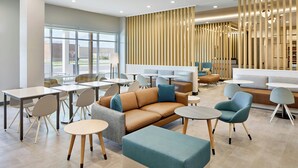 A modern lounge area with seating arrangements, tables, and a large window providing a view outside. - Towneplace Suites by Marriott Tullahoma (Tullahoma)