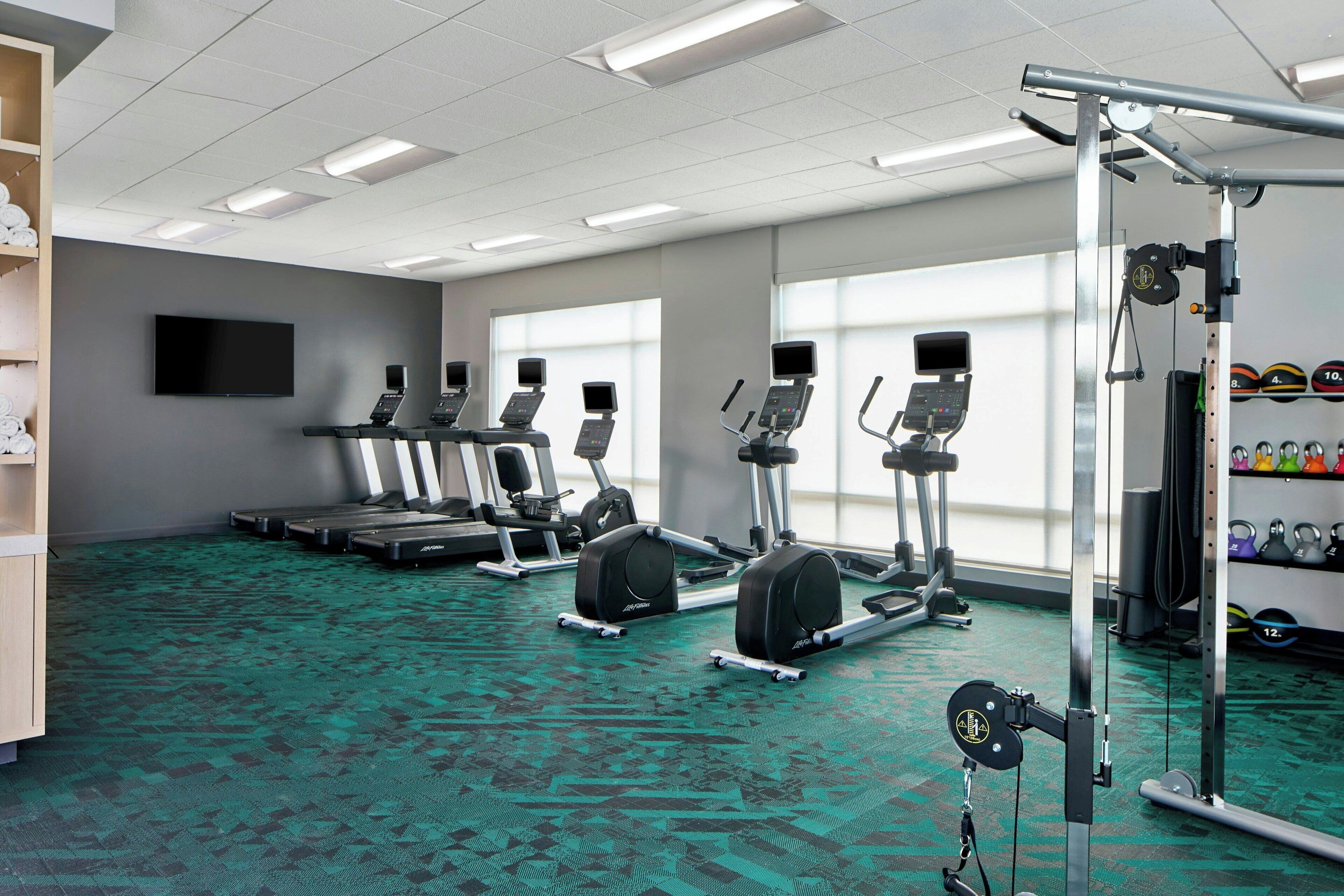 A gym with treadmills, elliptical machines, and weightlifting equipment.