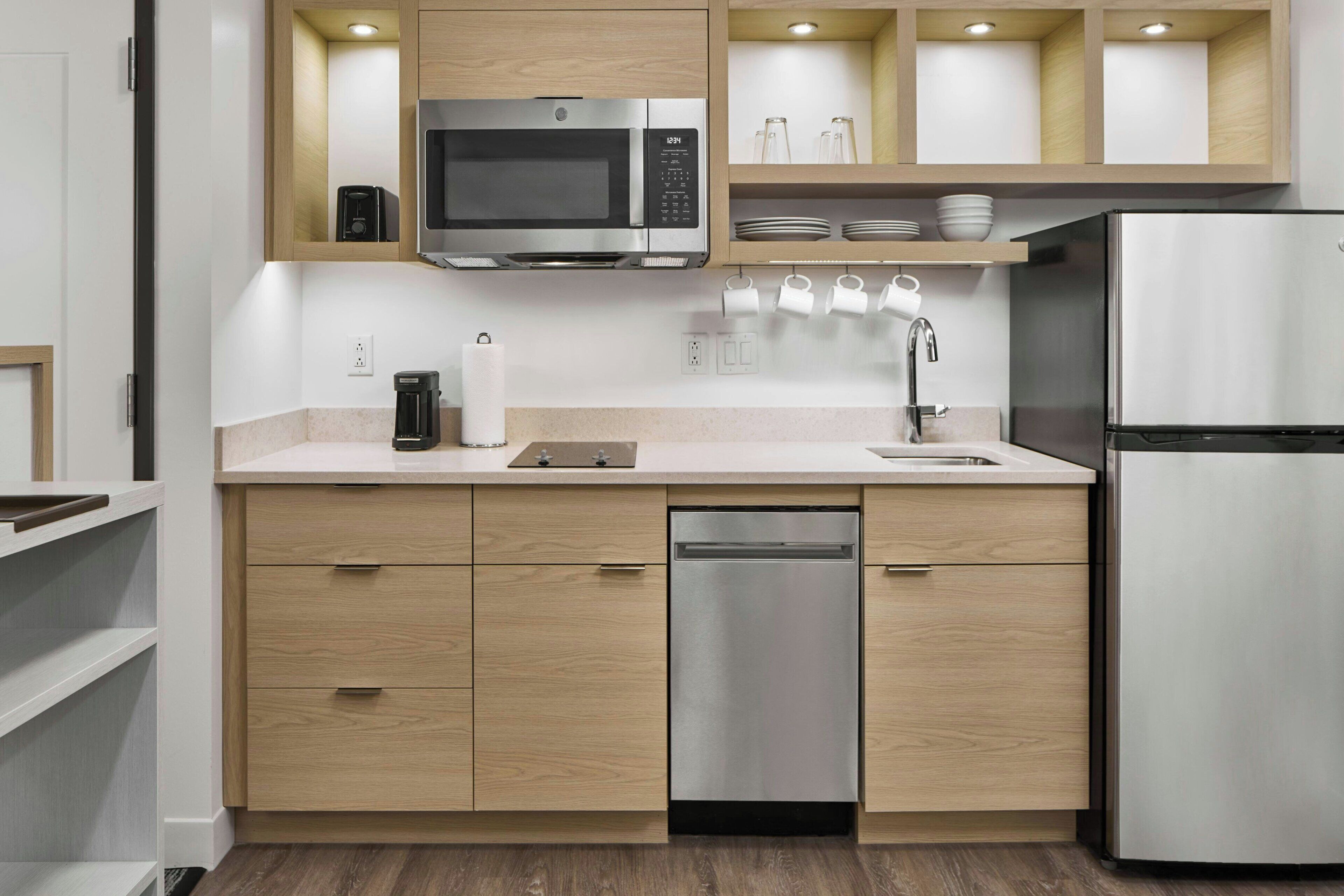 A modern kitchen with wooden cabinets, stainless steel appliances, and a built-in dishwasher.
