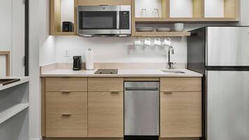 A modern kitchen with wooden cabinets, stainless steel appliances, and a built-in dishwasher.