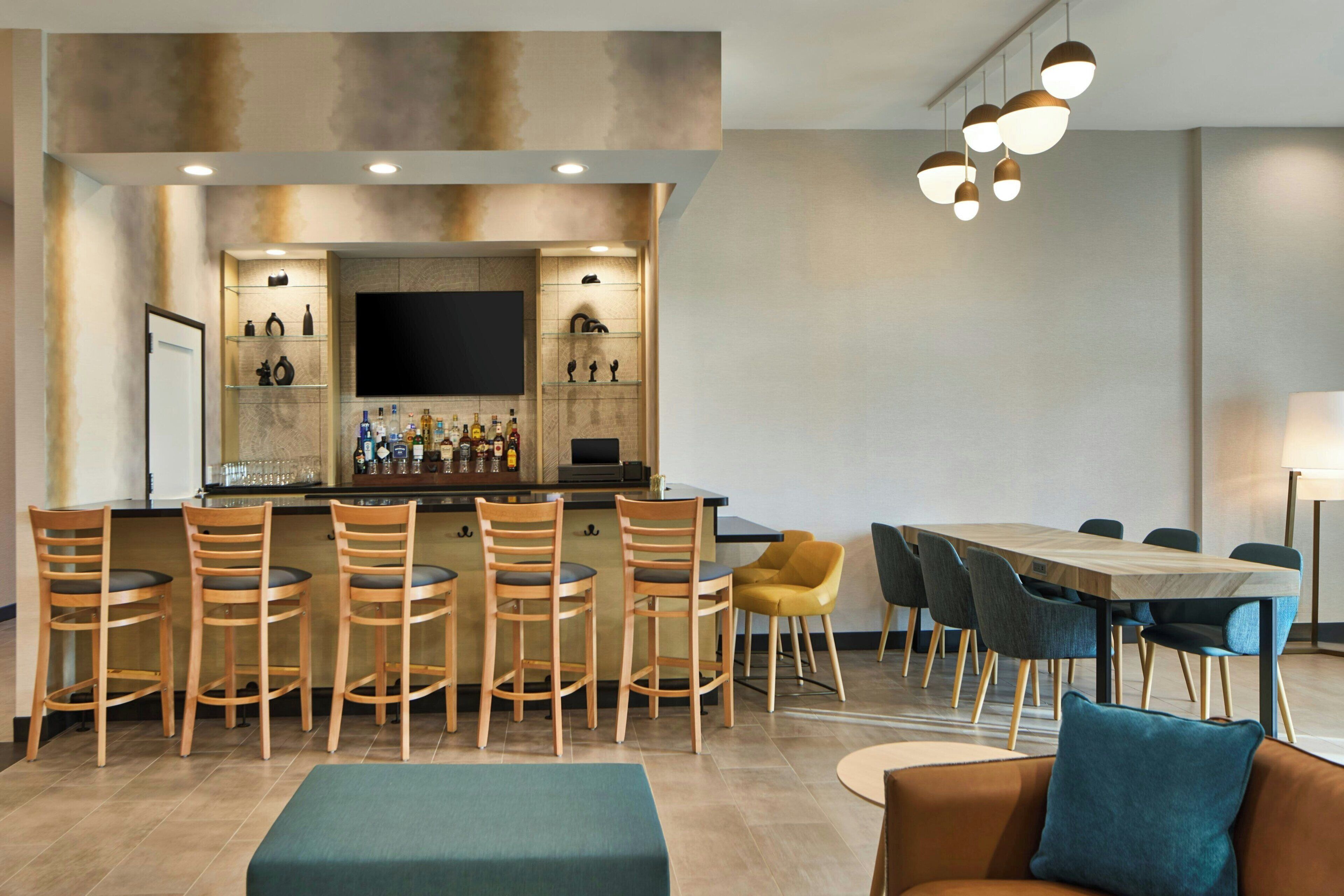 A modern bar area with a flat-screen TV, bar stools, and a dining table with chairs.