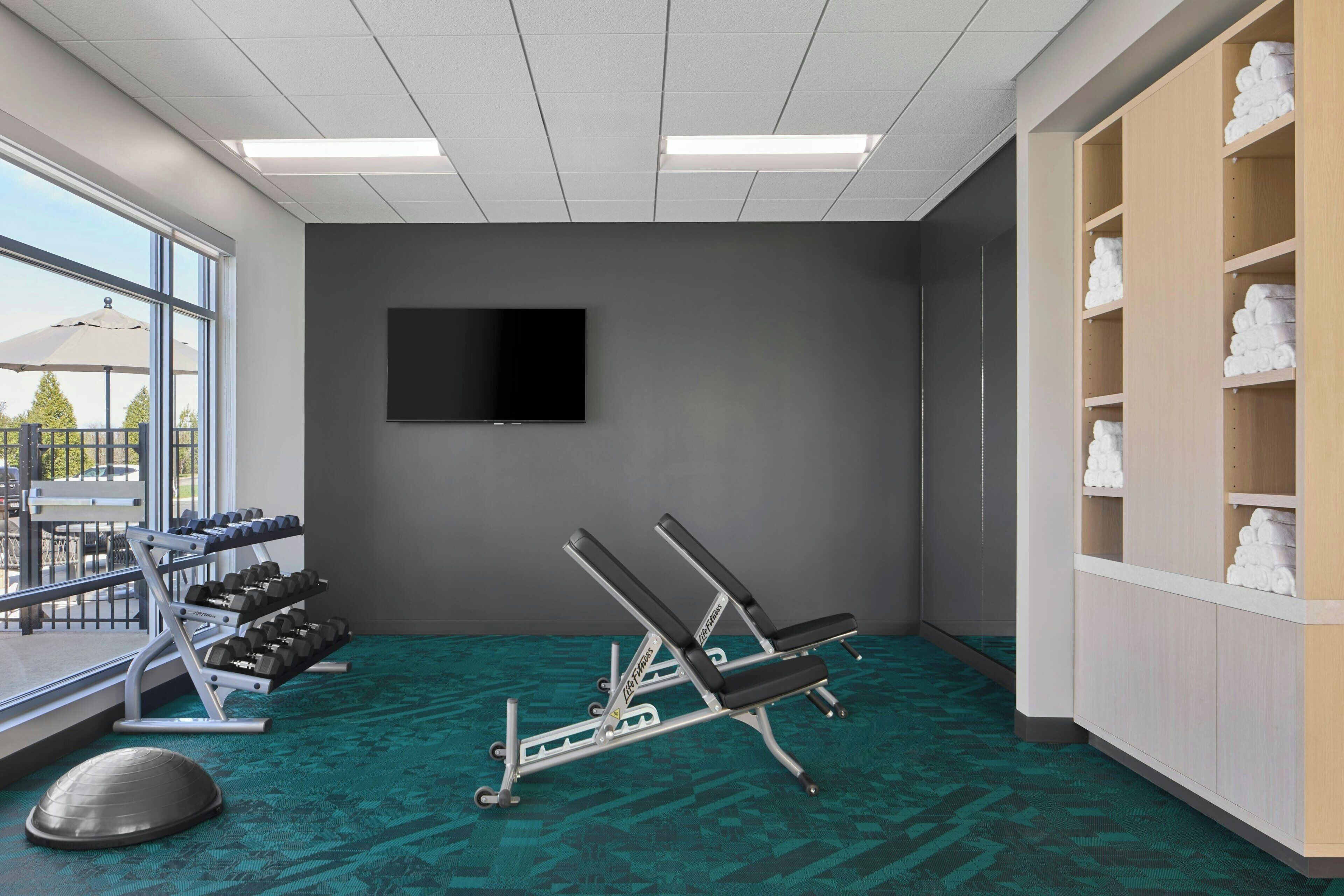 A gym with exercise equipment, a TV, and a view of the outdoors.