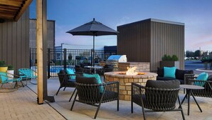 An outdoor patio with wicker chairs, a fire pit, and a grill.