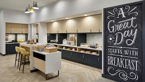 A modern kitchen with a breakfast bar, wooden cabinets, and a chalkboard sign.