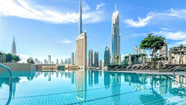 A swimming pool with a cityscape in the background, including tall buildings and clear skies. - DVH Luxe Retreat 4BR Burj View Apartment (Dubai)