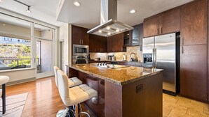 Una cocina moderna con una isla central, electrodomésticos de acero inoxidable y vistas al exterior.