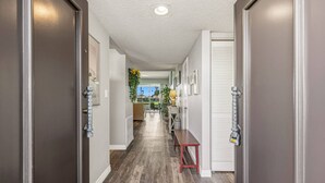A hallway with wooden flooring, a bench, and a door with a security device. - Gorgeous Two Bedroom in Rancho Las Palmas (Rancho Mirage)