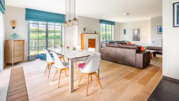 A modern living room with a dining area, large windows, and a cozy seating arrangement.