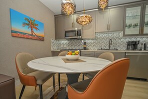 Una cocina moderna con microondas, cafetera y comedor con mesa redonda y sillas.