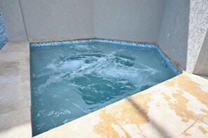 Un bain à remous doté d’un bord carrelé, entouré d’un mur à motifs et surmonté d’un sol carrelé.