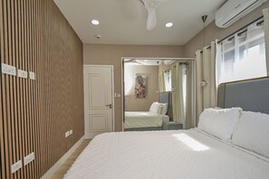 A hotel room with a large bed, a wardrobe, a mirror, and a ceiling fan. - 2BR Sugar Apple Suite | Villa-MSV | Pool, Kitchen & Sea Views – Family/Group (Saint George's)