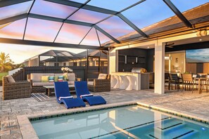 Un espace piscine avec des chaises longues, un bar et un coin salon offrant une vue sur le coucher de soleil.