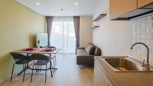 A compact kitchen with a sink, a dining area with chairs, a sofa, and a table with a vase.