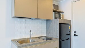 A compact kitchen with a built-in sink, a microwave, and a black refrigerator.