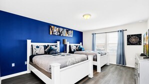 Ein Schlafzimmer mit zwei Betten, einer blauen Akzentwand und einer Deckenleuchte.