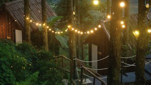 A rustic cabin surrounded by trees, with string lights hanging above. - D Home Sapa 10 (Sa Pa)