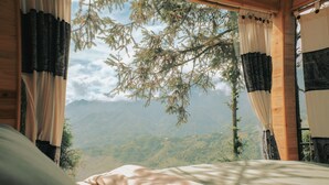 A bedroom with a bed, curtains, and a view of mountains. - D Home Sapa 10 (Sa Pa)