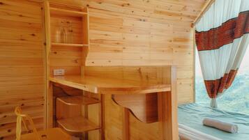 L'intérieur d'un chalet en bois, avec un lit, un bureau en bois et une chaise.