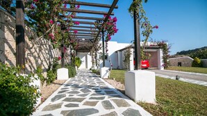 Un sendero de piedra que conduce a un edificio con una pérgola cubierta de flores rosadas.