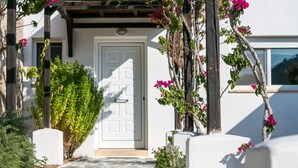 Un sendero de piedra que conduce a una puerta blanca con una pérgola de madera encima.