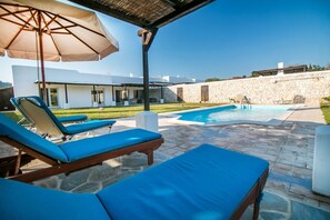 Uma área de piscina com espreguiçadeiras e um guarda-sol.
