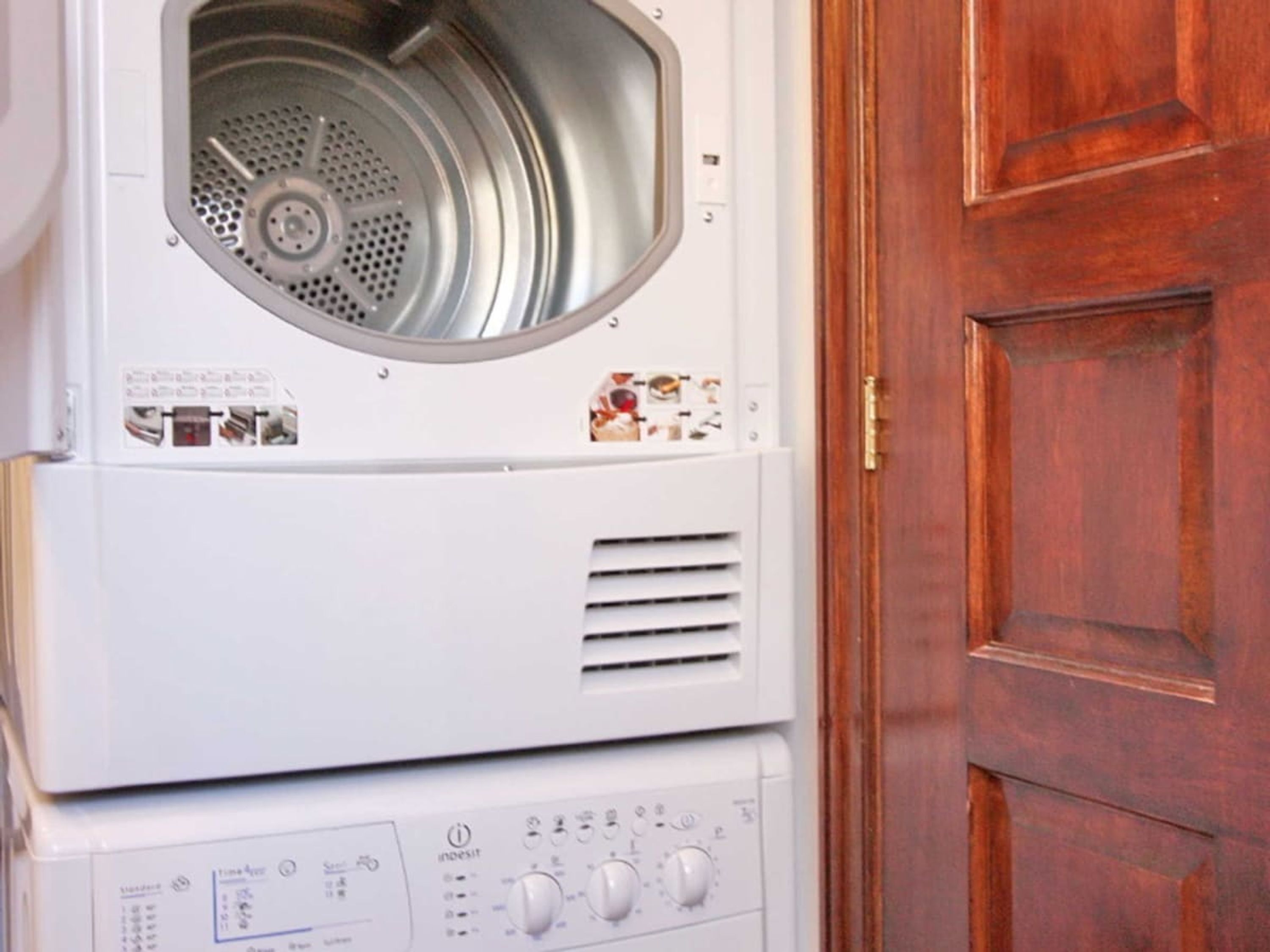 Un appareil combiné lave-linge et sèche-linge, de type « empilable », doté de boutons de commande et d’une porte.
