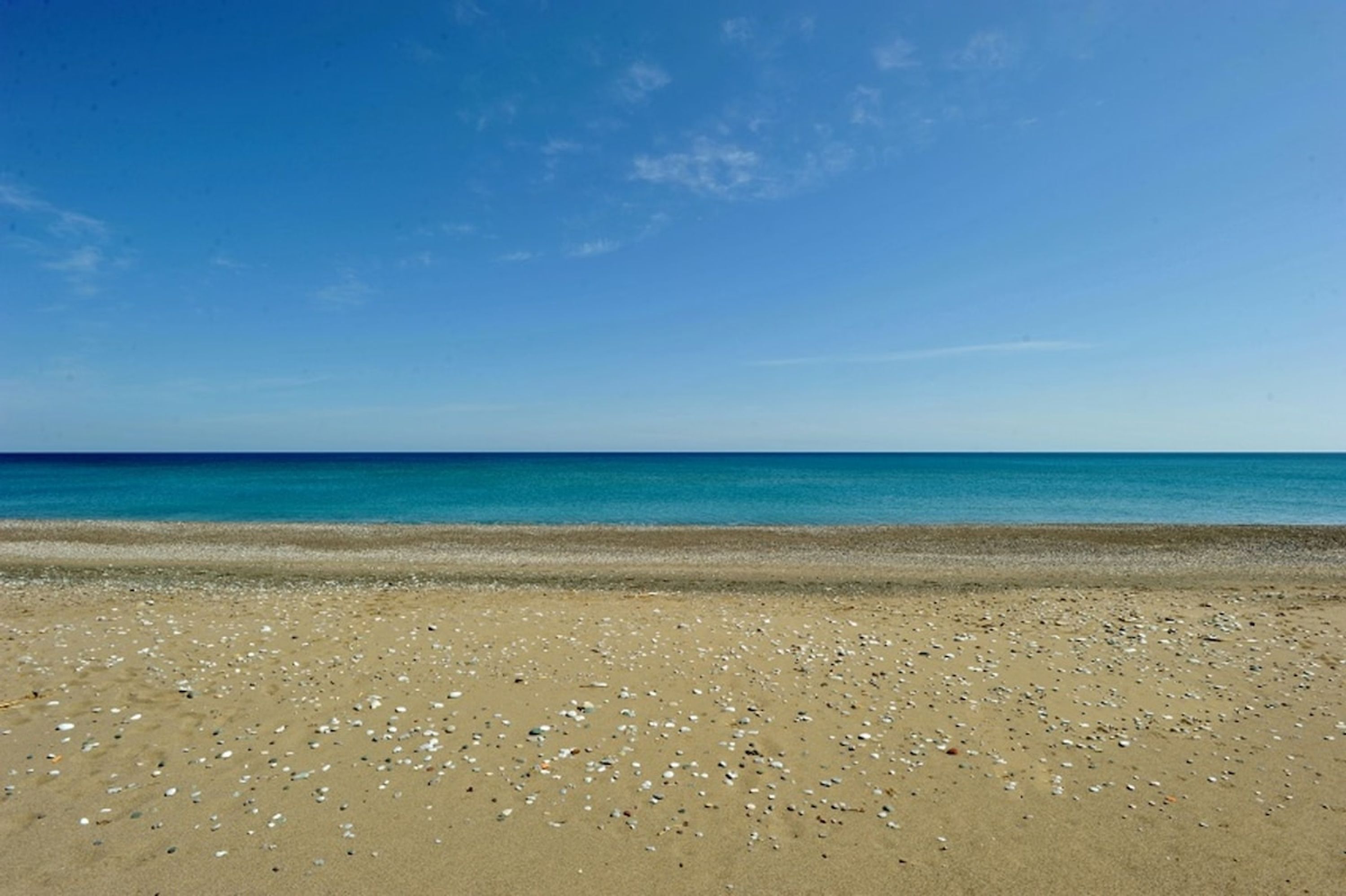 Een strand met een heldere lucht en een rustige zee.
