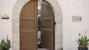Ein Steingewölbe mit zwei braunen Türen, einem Schild für 'Casa de la Hija' und einem QR-Code für Rhodes Vacation.