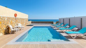 A pool area with lounge chairs and a view of the sea. - The Cottage South Escape With Beach Front Pool (Rhodes)