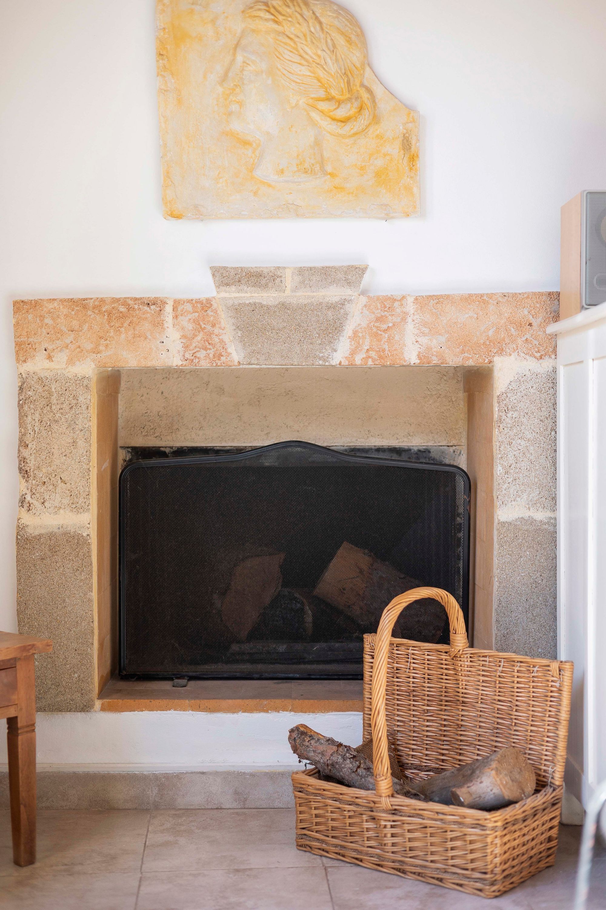 A stone fireplace with a basket of firewood and a woven basket beside it.