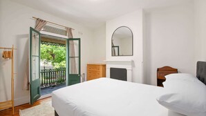 Une chambre à coucher comprenant un lit, une commode, un miroir et une porte donnant sur un balcon.