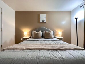 A neatly made bed with a headboard, two bedside lamps, and a framed picture on the wall. - Pocolonial Charming 4BR Mountain Retreat (Albrightsville)