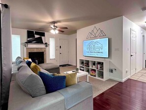 Un salon avec un canapé, un téléviseur fixé au mur et une cheminée.