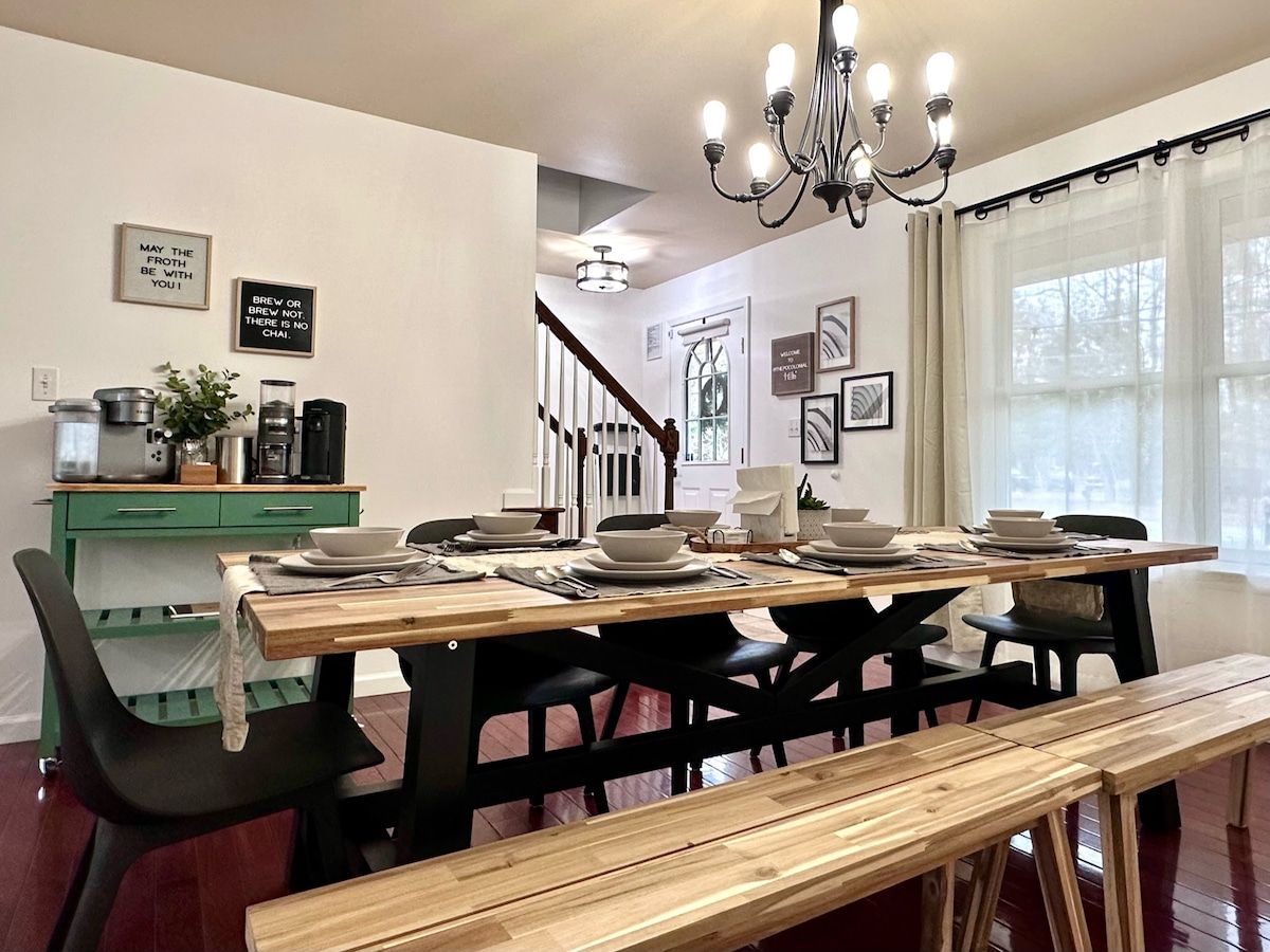 A dining area with a wooden table set for four, black chairs, a green cabinet, and a chandelier.