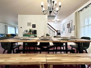 Ein Essbereich mit einem Holztisch, gedeckt für vier Personen, schwarzen Stühlen und einer Kristallleuchter.