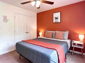 A bedroom with a bed, a ceiling fan, a door, and a nightstand with a lamp. - Pocolonial Charming 4BR Mountain Retreat (Albrightsville)