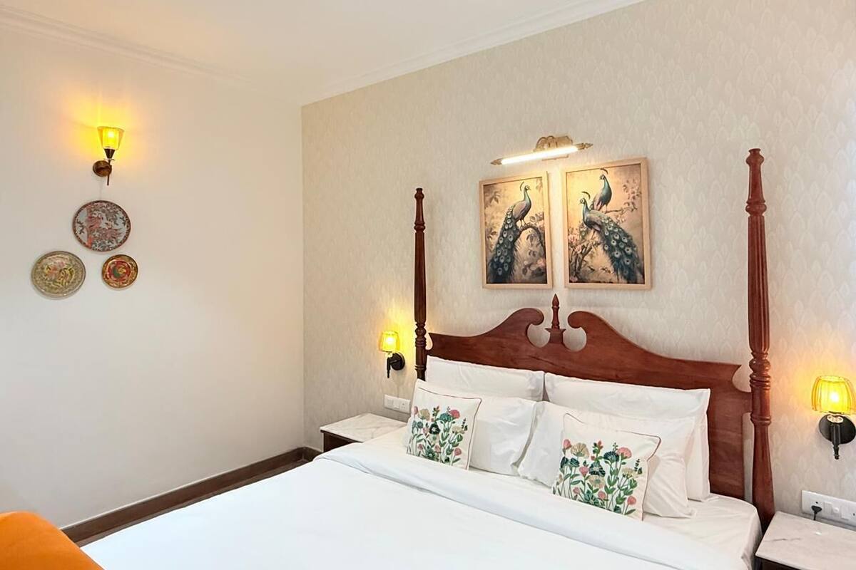 Une chambre d’hôtel avec un lit à baldaquin, deux lampes fixées au mur et des œuvres d’art décoratives accrochées au mur.