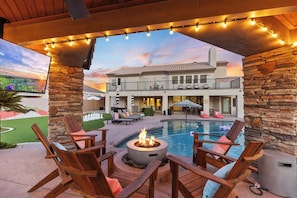 A poolside area with wooden chairs, a fire pit, and string lights. - Luxury 6BR Retreat - Pool, BBQ, Theater and Games (Mesa)