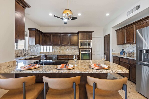 A modern kitchen with dark wood cabinets, stainless steel appliances, and a granite countertop.
