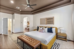 A spacious bedroom with a large bed, a ceiling fan, and a bench. - Luxury 6BR Retreat - Pool, BBQ, Theater and Games (Mesa)