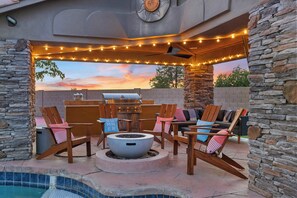 An outdoor patio with stone walls, a fire pit, and string lights.