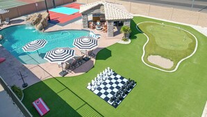 Zwembad met fontein, putting green en een groot spel met een schaakbordpatroon.